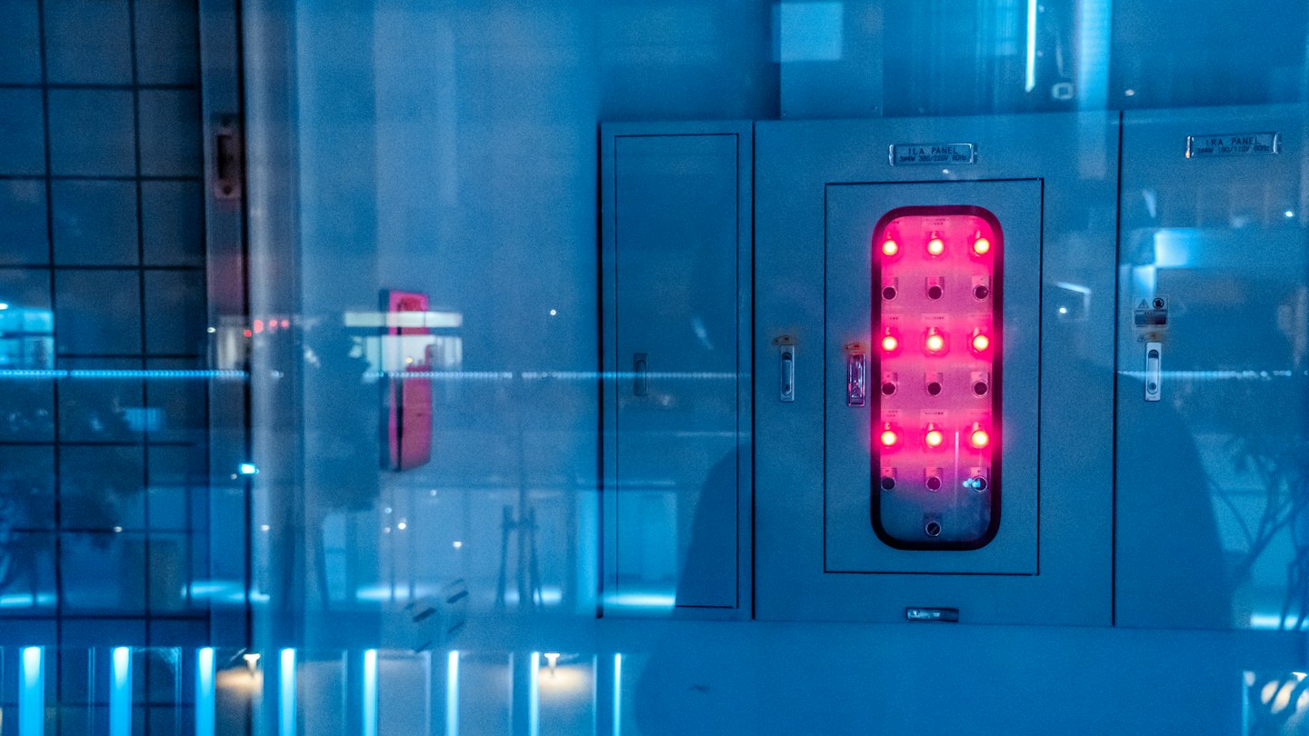 Endüstriyel bir elektrik kontrol panelindeki parlayan kırmızı gösterge ışıkları.