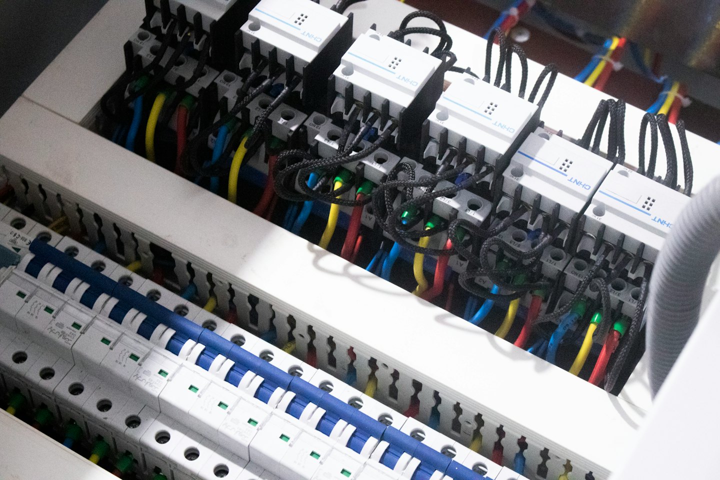 Devre kesiciler ve renkli kablolarla elektrik kontrol paneli.